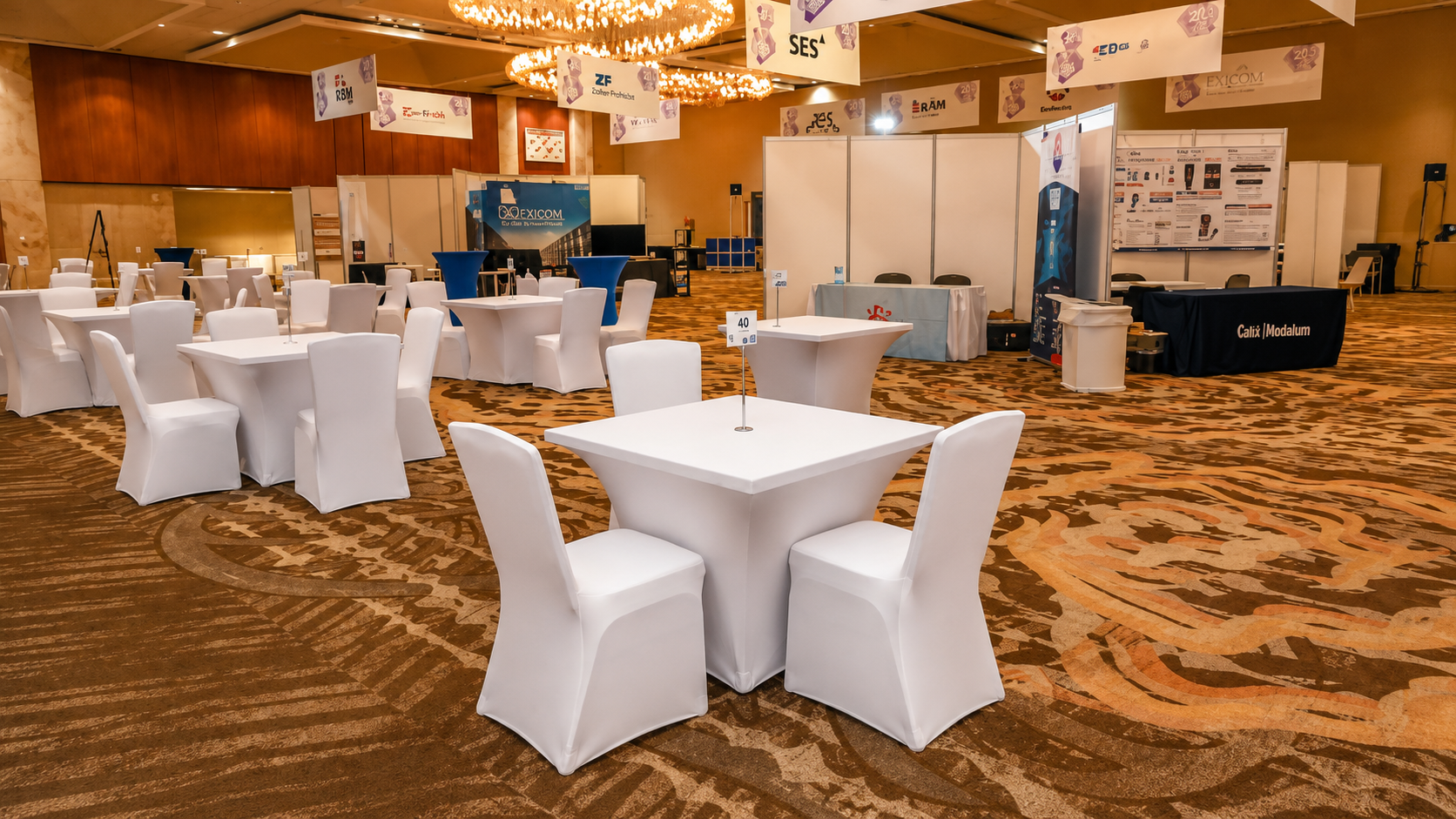 Conference show floor with sponsor booths and chandelier lighting, run by Savvy Coordination