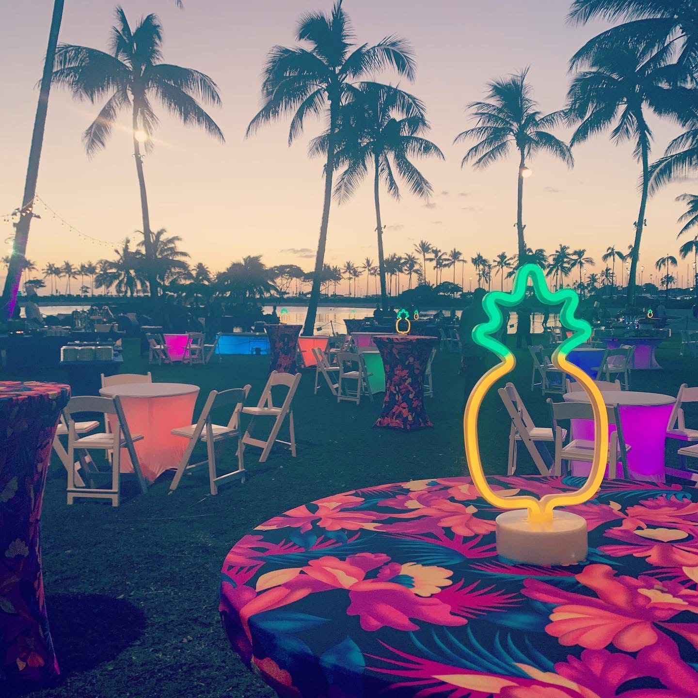Outdoor sunset reception at the PTC conference with palm trees and illuminated cocktail tables